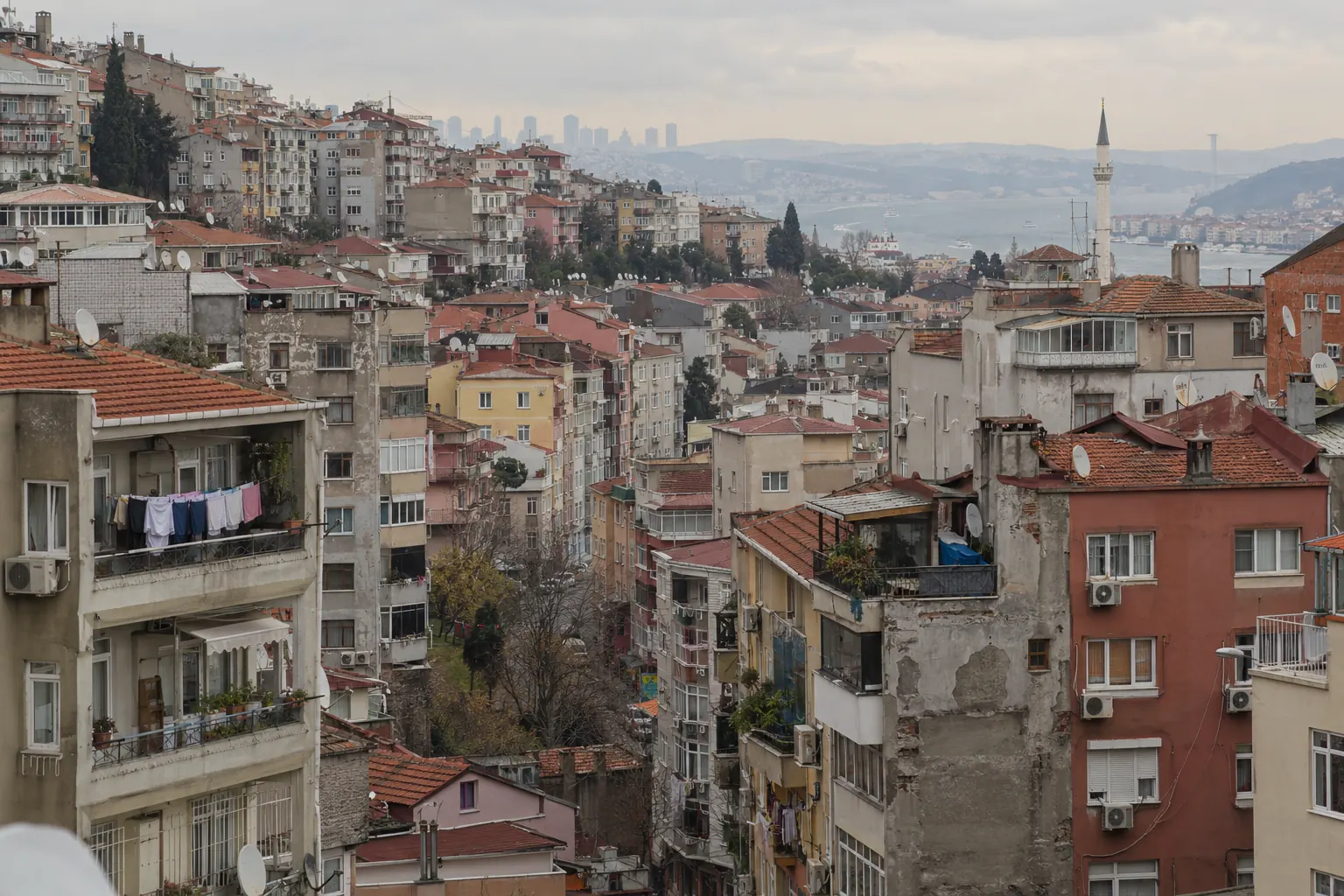 İstanbul'da yamaca kurulmuş yoğun apartman dokusu, uzakta Boğaz